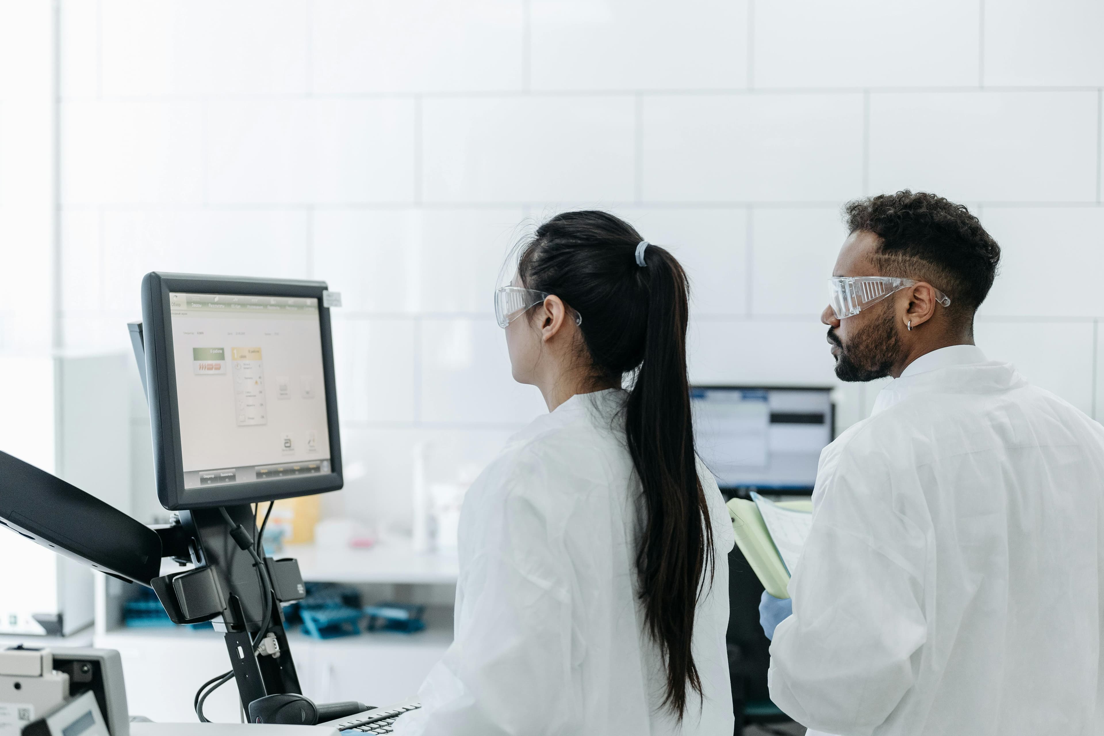 Pesquisadores em laboratório utilizando estação de trabalho para análise de dados.